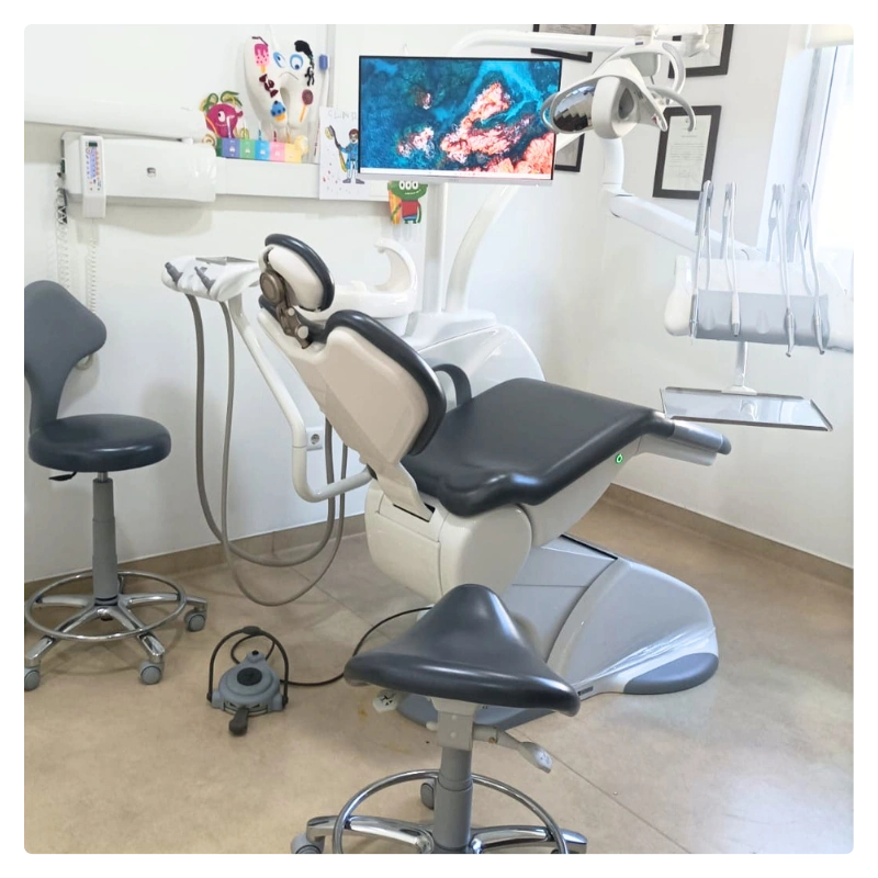 Dental treatment chair with attached monitor and dental instruments in a clean clinic.