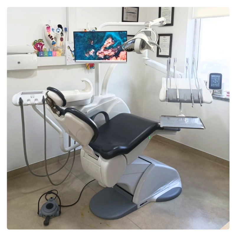 Dental examination chair with monitor, overhead light, and dental instruments in a clean clinic.